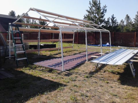 1995 Ford Bronco - Outdoor construction of a metal carport frame, with materials laid out on the ground.