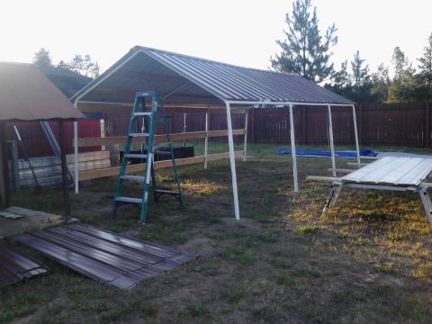1995 Ford Bronco - Construction of a metal carport is underway, with materials and tools laid out in the yard.