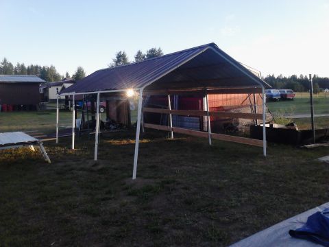 1995 Ford Bronco - Three vehicles are visible in the distance behind a metal carport on a sunny day.