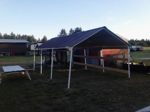 1995 Ford Bronco - A metal carport covers a storage area, with several vehicles visible in the distance under a clear sky.