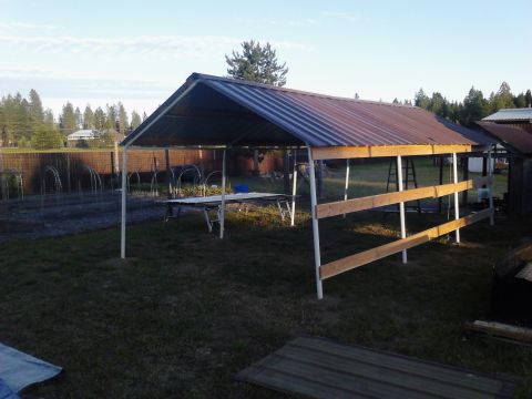 1995 Ford Bronco - Carport structure in a yard with garden beds and fencing visible.