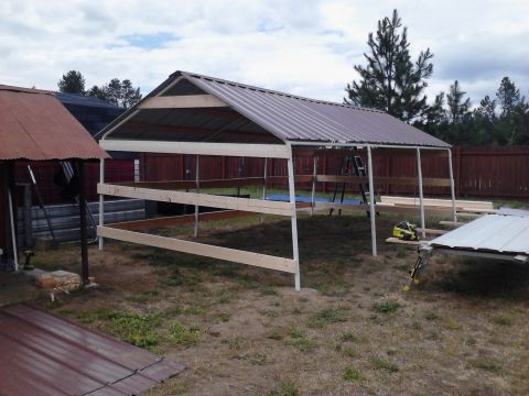 1995 Ford Bronco - A partially constructed carport with a metal roof and wooden framing is shown outdoors.