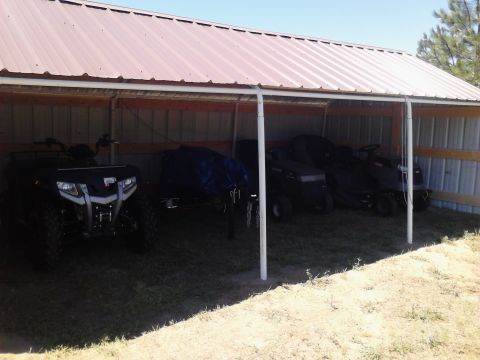 1995 Ford Bronco - Several vehicles, including an ATV and lawn tractors, are parked under a covered shelter.
