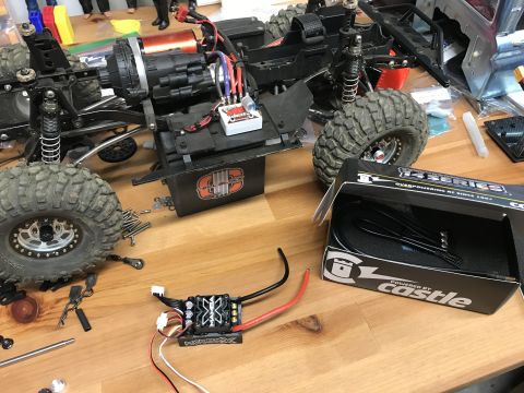 1989 Ford Bronco - RC car parts and chassis assembly on a workbench, including a Castle Creations ESC.