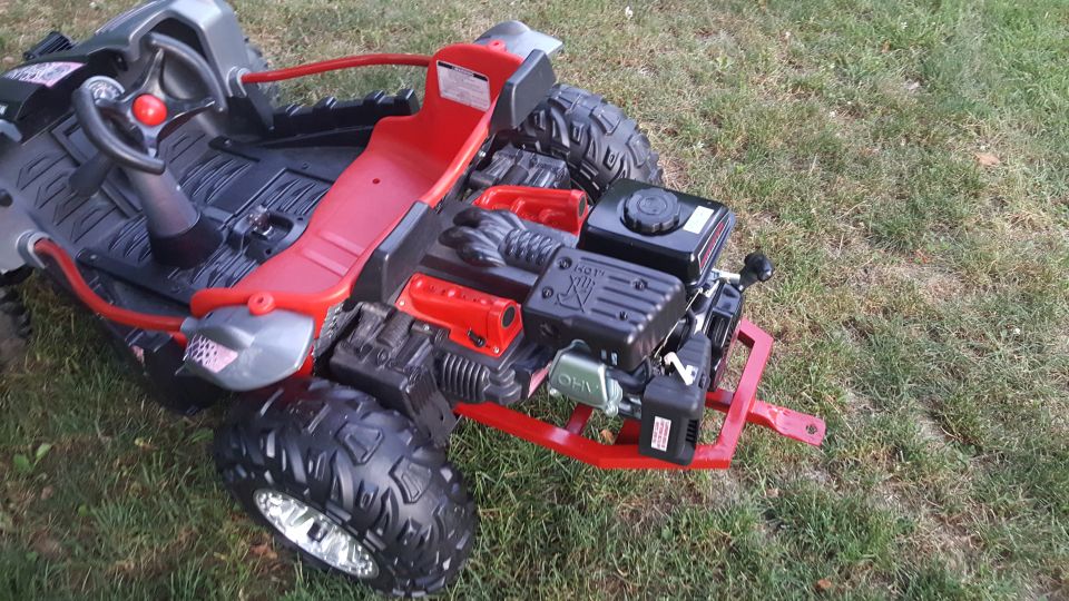Go-kart with red seat and exposed engine, parked on grass. Supermotors.net logo visible