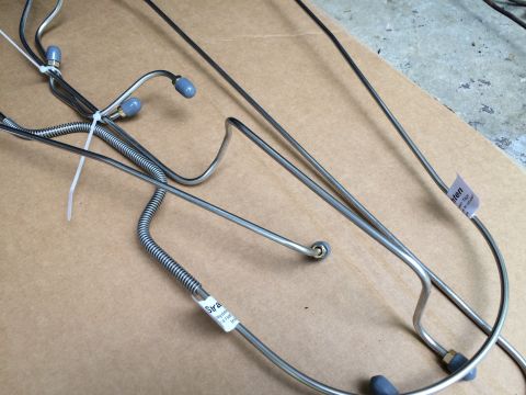 1970 Ford Ranchero - Several metal brake lines are laid out on a cardboard surface, some with blue protective caps.