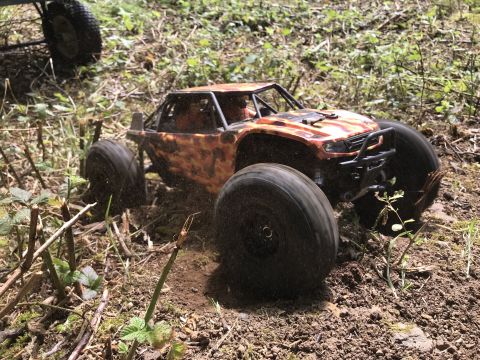 1989 Ford Bronco - A remote control buggy with an orange camouflage body navigates a dirt path through foliage.