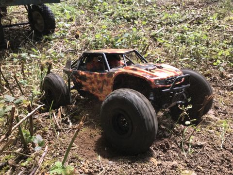 1989 Ford Bronco - RC rock crawler with large tires navigates a dirt and grass terrain.