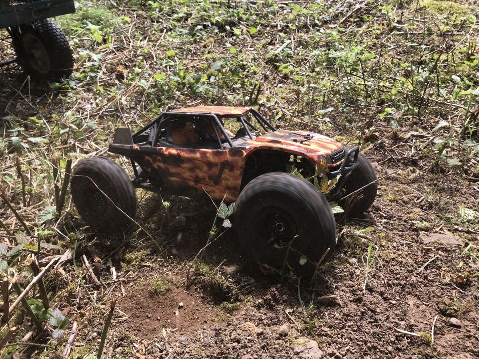 RC rock crawler with camouflage paint on dirt and grass