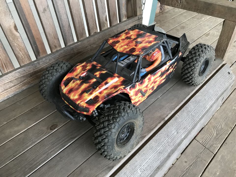 RC rock crawler with flame graphics on a wooden deck
