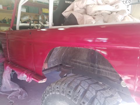 1968 Ford Bronco - Side view of a red 1968 Ford Bronco undergoing restoration, showing the body panel and tire.