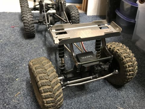 1989 Ford Bronco - Close-up of an RC rock crawler's chassis and suspension system, showing its off-road tires and steering servo.