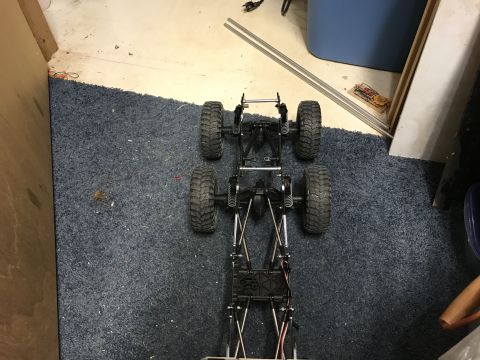 1989 Ford Bronco - The chassis of an RC car is shown from a top-down perspective on a blue carpet.
