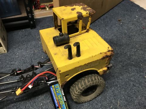 1989 Ford Bronco - A yellow toy truck with a weathered appearance, a visible battery pack and dual exhaust pipes.