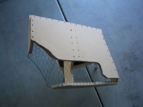 1989 Ford Bronco - A custom-built subwoofer enclosure, constructed from wood and chicken wire, is shown resting on a concrete surface.