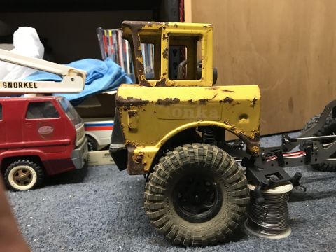 1989 Ford Bronco - A weathered yellow toy truck with 'Tonka' visible on its side sits beside a red toy truck.
