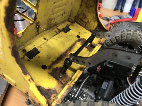 1989 Ford Bronco - Close-up view of the interior chassis of a yellow RC car, showing suspension and steering linkages.