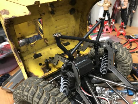 1989 Ford Bronco - Close-up view of an RC rock crawler's chassis and suspension system, showing its internal components and tires.