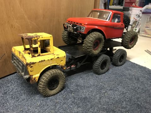 1989 Ford Bronco - A red pickup truck is mounted on a yellow Tonka toy truck chassis, creating a custom six-wheel vehicle.
