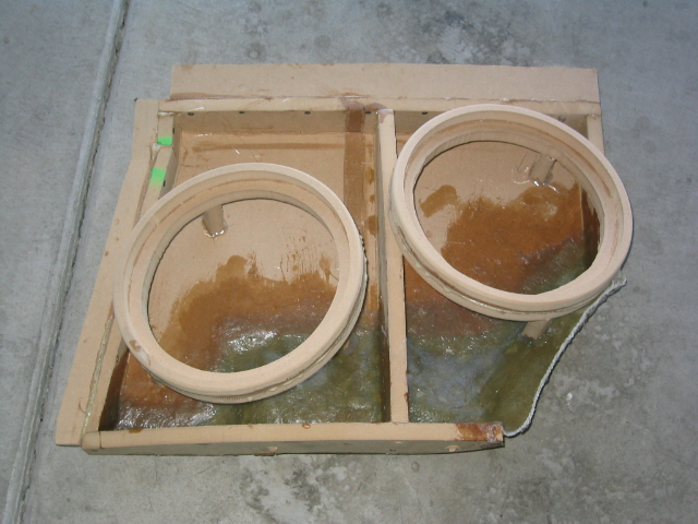 Fiberglass subwoofer box mold in progress with two round speaker rings and resin-coated base