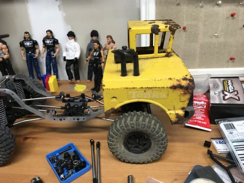 1989 Ford Bronco - Workbench with a yellow Tonka toy truck body, chassis, action figures, and various parts.