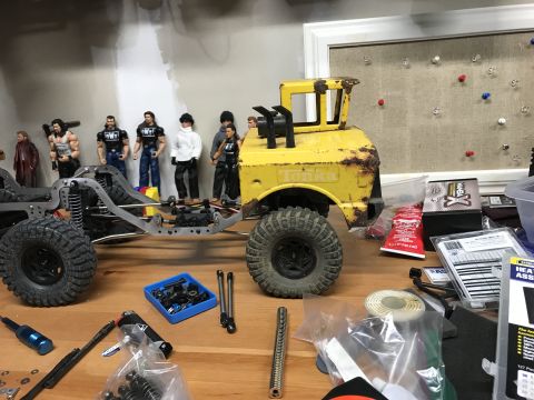 1989 Ford Bronco - A workbench is set up with parts and tools for building an RC truck, a partially assembled chassis and a vintage Tonka truck body.