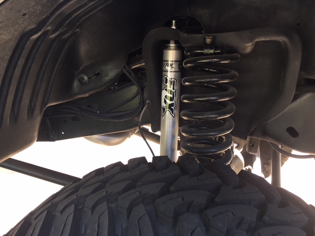 Close-up of a black coil spring and silver FOX shock absorber on a vehicle's suspension