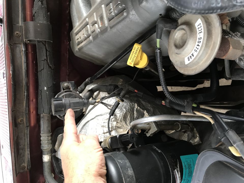 1996 Ford F-150 engine bay with a hand pointing to a sensor