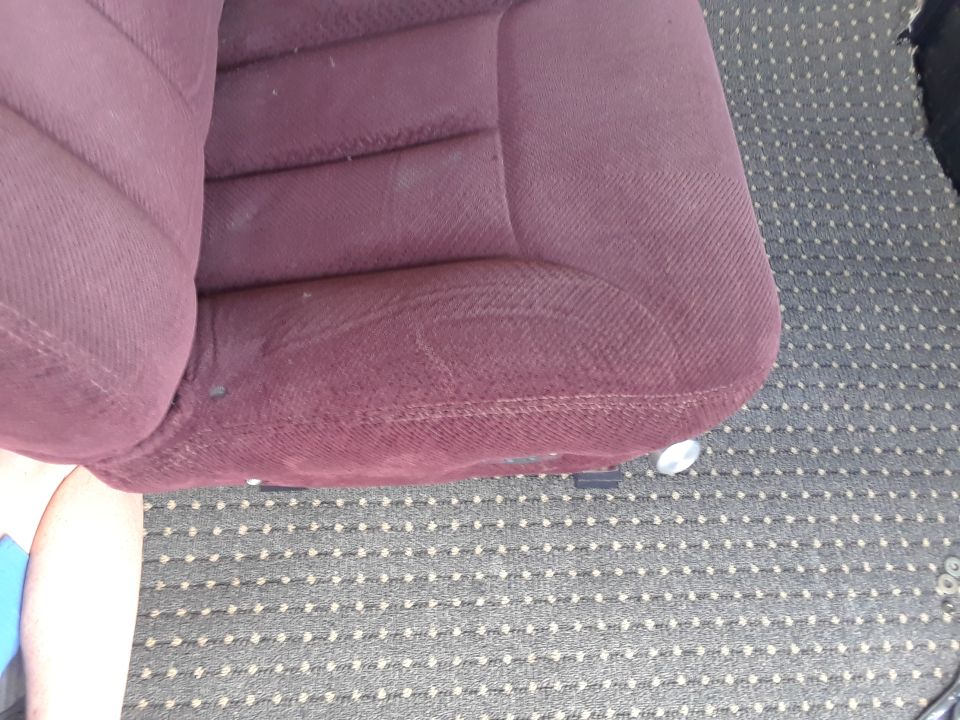 Close-up of a maroon vehicle seat and patterned carpet