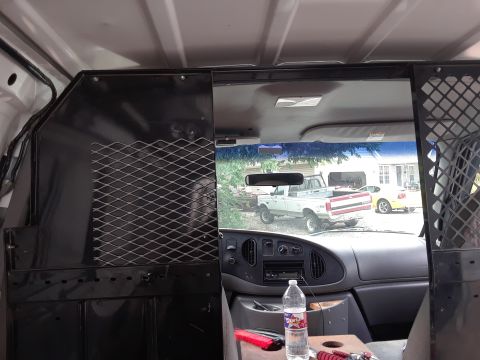 1999 Ford E250 - Interior view of a van showing a partition and a view of two vehicles parked outdoors.