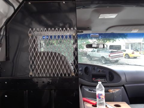 1999 Ford E250 - View from inside a van, looking through the windshield at two other vehicles parked outside.