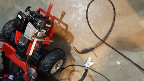 2007 Subaru Impreza - A red ATV part with an engine and large tires sits on a concrete floor next to a black cable.