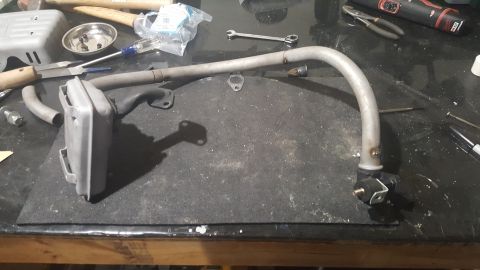 2007 Subaru Impreza - An exhaust pipe and muffler assembly is laid out on a workbench with tools.