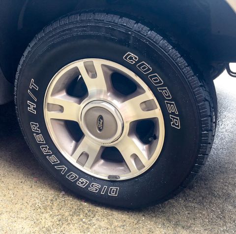 2003 Ford Explorer - Close-up of a vehicle's wheel Cooper Discoverer H/T tires and a Ford center cap.