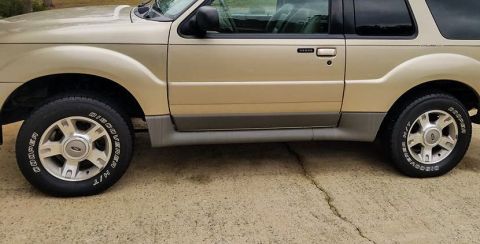 2003 Ford Explorer - Side view of a gold 2003 Ford Explorer, parked on a concrete surface.