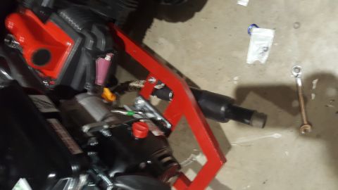 2007 Subaru Impreza - A red bracket is attached to a black engine part, with a wrench and other items on the floor nearby.