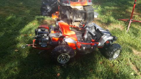 2007 Subaru Impreza - An orange ATV with a trailer hitch is parked on grass next to a lawnmower.
