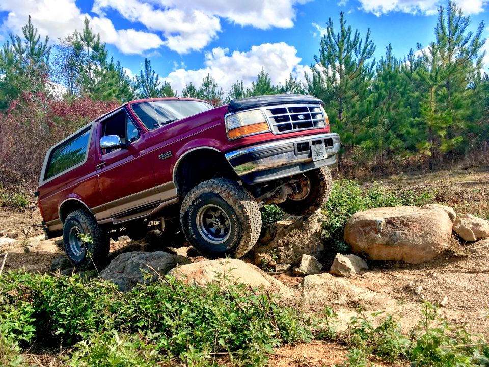 Red 1995 Ford Bronco navigating rocky terrain