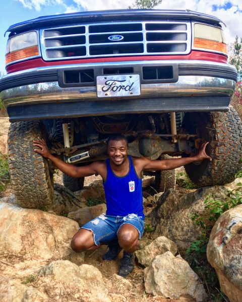 1995 Ford Bronco - A man poses in front of a lifted Ford truck, showing off its off-road capabilities.