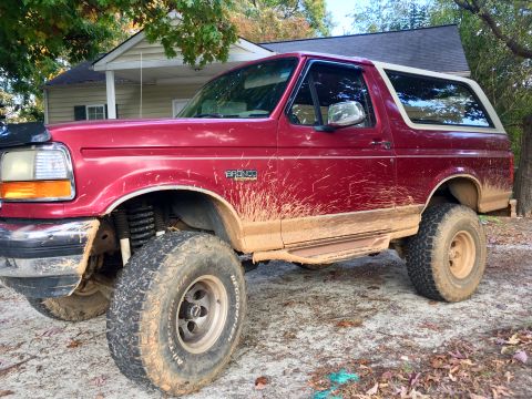 1995 Ford Bronco - This red Ford Bronco has seen some off-road action, evidenced by the mud covering its body and tires.
