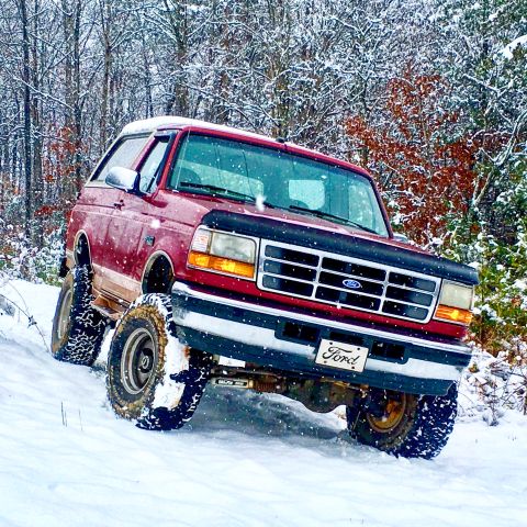 1995 Ford Bronco - A red 1995 Ford Bronco navigates a snowy, wooded trail.