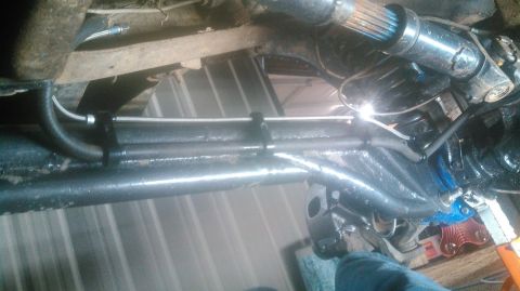 1978 Ford Bronco - Underneath view of a vehicle's suspension and drivetrain components, showing brake lines and a driveshaft. The vehicle appears to be on jac…