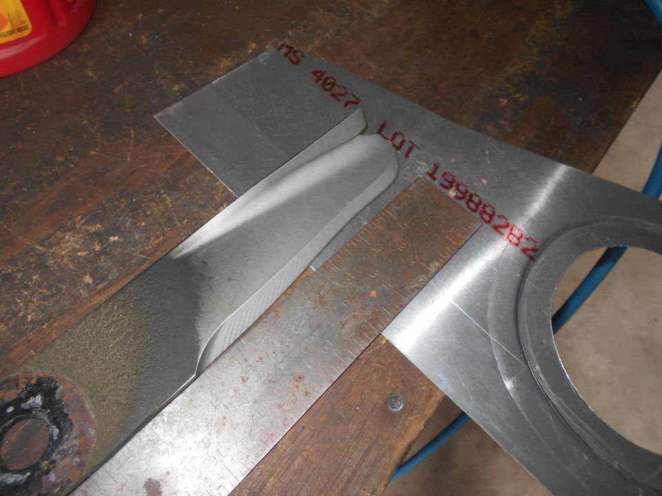 Lawn mower blade being measured with a square and ruler on a workbench.