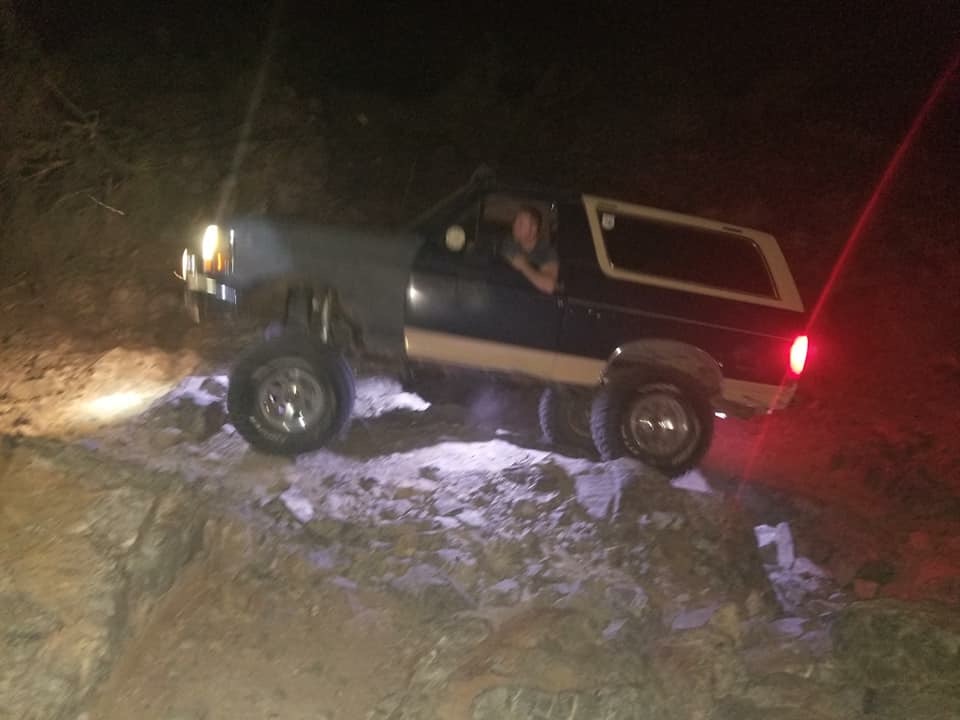 1991 Ford Bronco off-roading at night on a rocky trail.