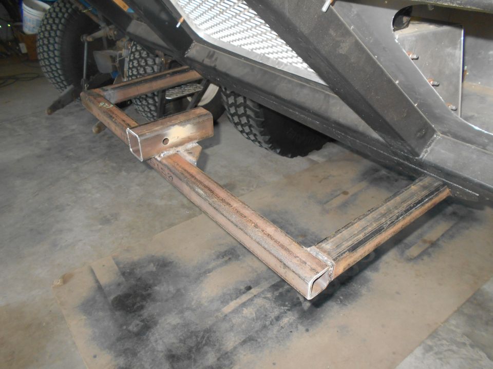 Close-up of a custom steel step/hitch extension welded to the frame of an off-road vehicle.