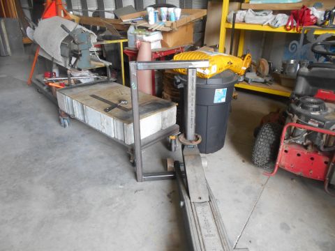 1992 Ford Bronco - A metal frame structure is positioned over a hydraulic jack in a workshop setting. Various tools and equipment are visible in the backgroun…