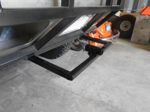1992 Ford Bronco - A black metal trailer hitch receiver is attached to the rear of a trailer. The trailer has large tires and a metal bed.
