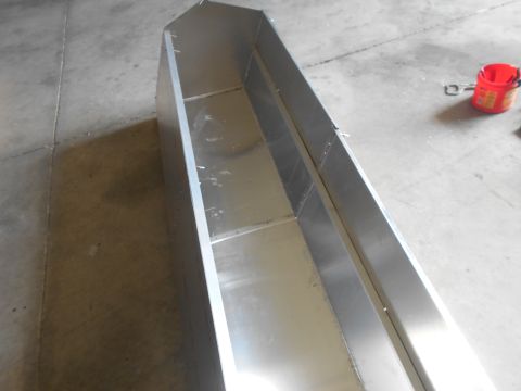 1992 Ford Bronco - A long, narrow, metallic trough-like object sits on a concrete floor. A red bucket with a metal handle is visible in the background.