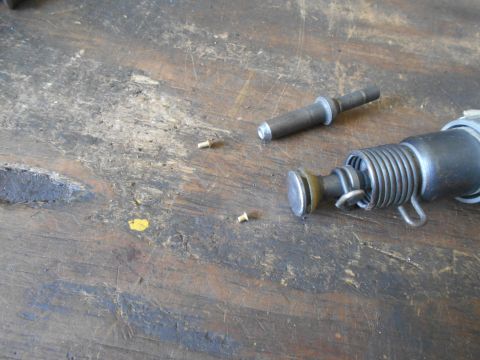 1992 Ford Bronco - A close-up shot shows disassembled parts of a tool, possibly a rivet gun, lying on a weathered wooden surface. The parts include a cylindri…