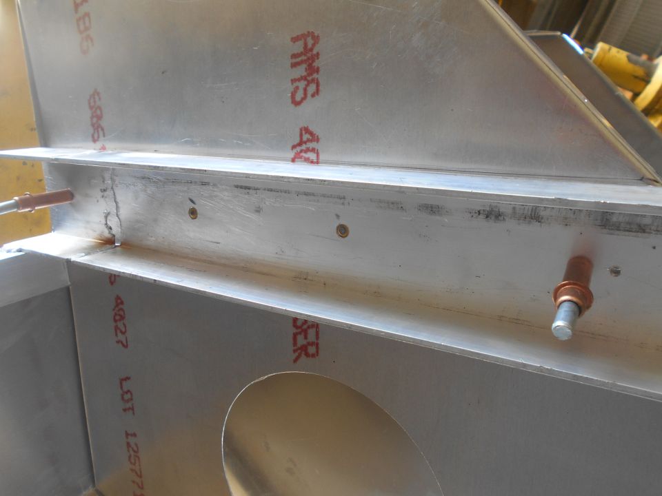 Close-up of aluminum structural components with red markings and rivets.